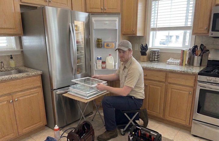 Technician servicing an open French-door refrigerator in a Bellingham kitchen