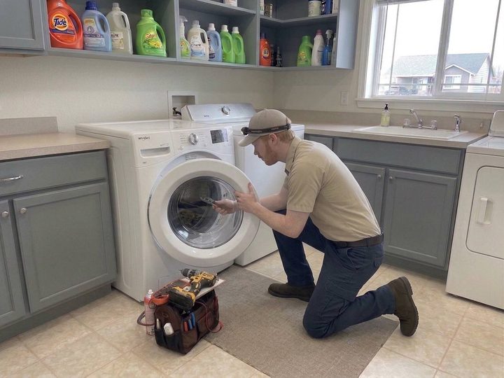 Technician inspecting a front-load washer drum with a headlamp